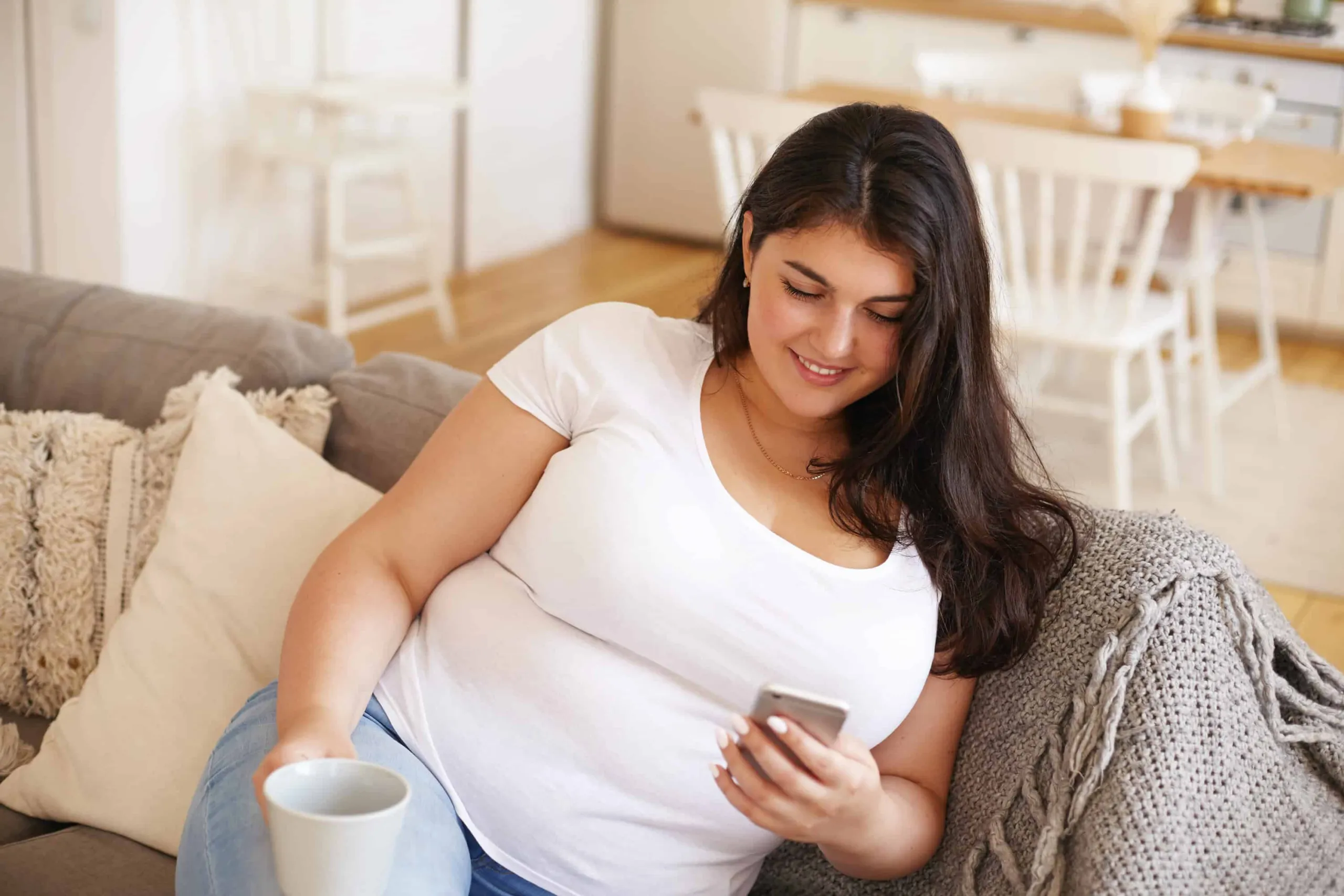 A patient at home with a phone and a cup of coffee